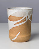 Ceramic cup with brown and white design on a gray background