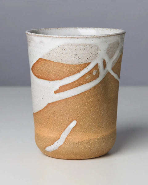 Ceramic cup with brown and white design on a gray background