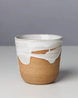 Ceramic cup with white top and brown bottom on a gray background