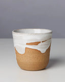 Ceramic cup with white top and brown bottom on a gray background