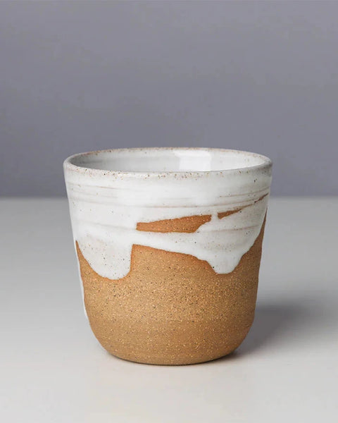 Ceramic cup with white top and brown bottom on a gray background