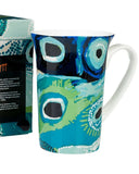 Colorful mug with peacock feather design next to its packaging on a white background
