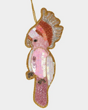 Decorative ornament shaped like a seahorse with pink and gold details on a white background
