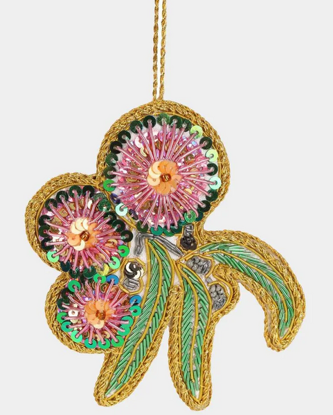 Decorative flower ornament with pink centers, green leaves, and gold accents on a white background